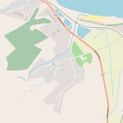 GIF animé d'une carte OpenStreetMap, le village de Songbuk-ri au sud de la baie de Corée, dans le Kangwon, au sud-est de la Corée du Nord, à quelques kilomètres de la frontière avec la Corée du Sud.

Première image : la principale route est présente au nord, avec quelques routes résidentielles et la ligne de chemin de fer plus au nord. La zone résidentielle est grossièrement faite. Il n'y a presque aucun bâtiment, et on remarque une petite zone de cimetière à l'ouest et de champs à l'est.

Deuxième image : tous les objets sont intégralement redessinés sauf le trait de côte au nord, soit : tous les bâtiments, toutes les routes, tous les cours d'eau. De nombreux bâtiments et zones de forêt apparaissent.