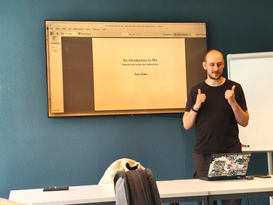 Picture of Yvan Sraka with thumbs up next to the opening slide with title "An introduction to Nix" and subtitle " Reproducible builds and deployments"
