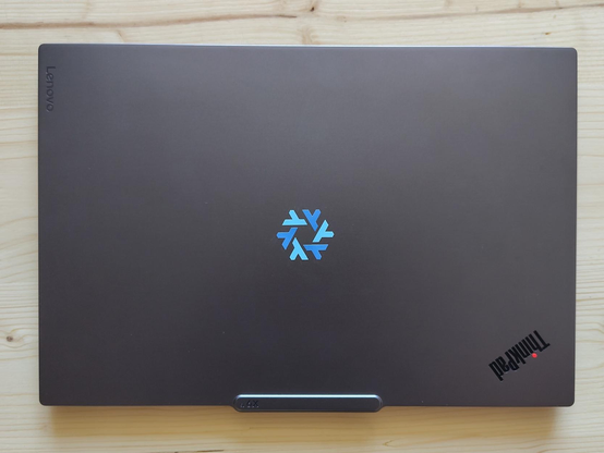 Picture of a closed grey laptop (ThinkPad) with a NixOS Sticker in the center of the lid